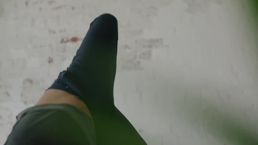 Bearded man wearing sports clothes doing yoga balances standin on his hands inside a room