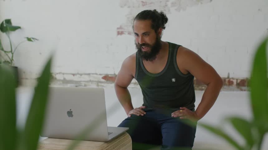 A man is laughing as he talks on the laptop