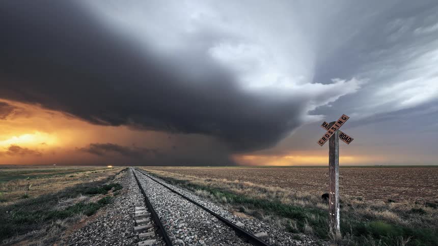 Dark clouds floating over a rural field during a rainstorm at sunset