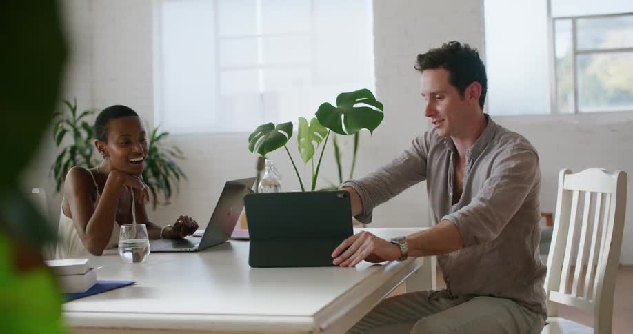 A man and woman sitting at a desk and working on computers