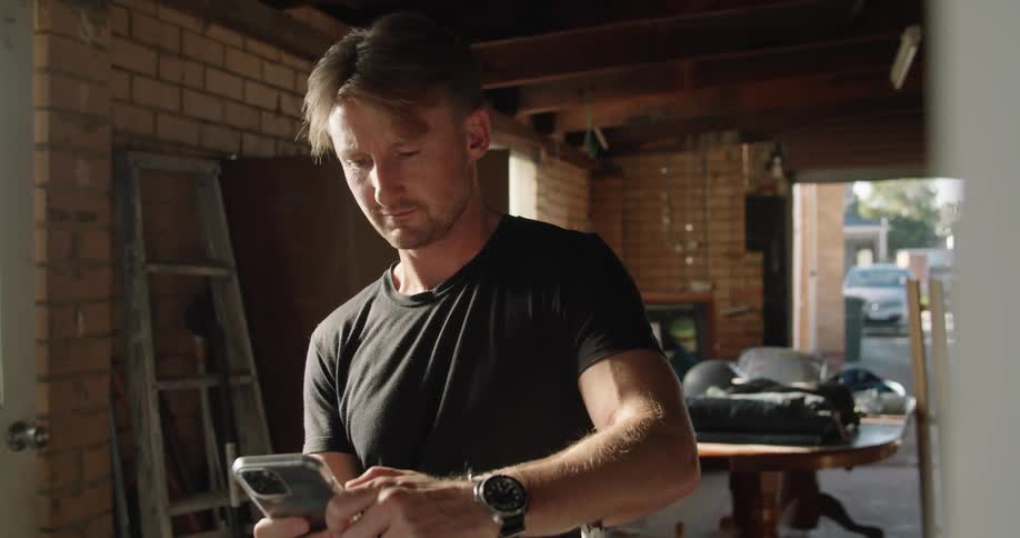 A man stands in his garage and uses his cell phone
