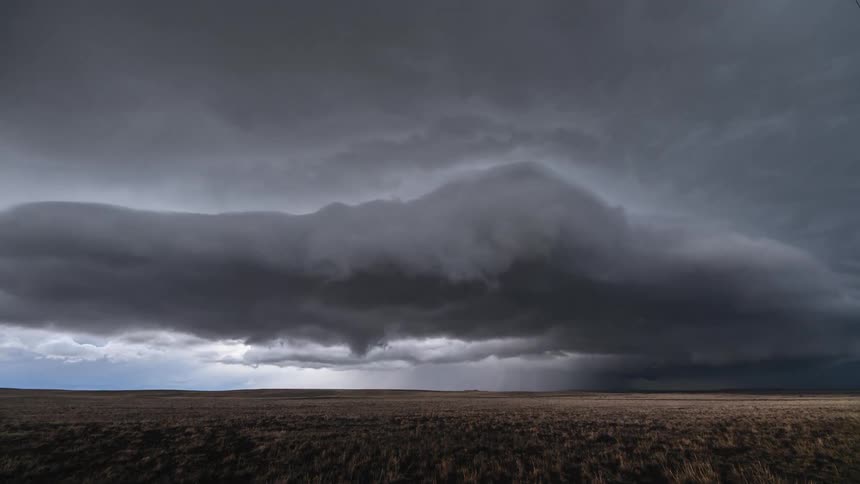 Dark clouds spin over a field as a storm comes in and day turns into night