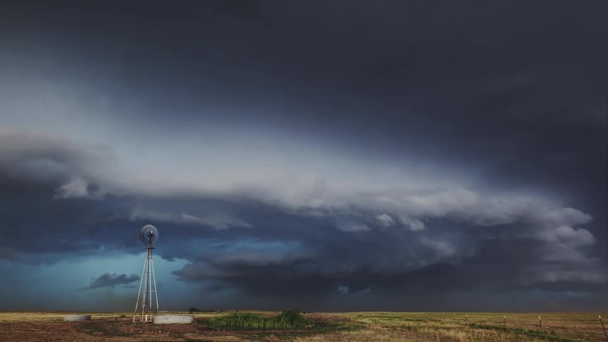 Multiple lightning bolts strike down onto a rural field near a windmill