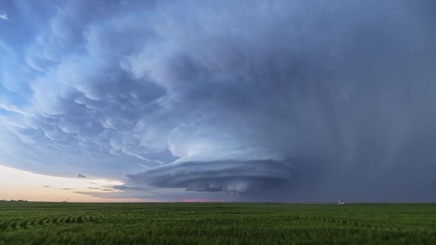 Lighting flashes from tornado clouds spinning in the air over farmland