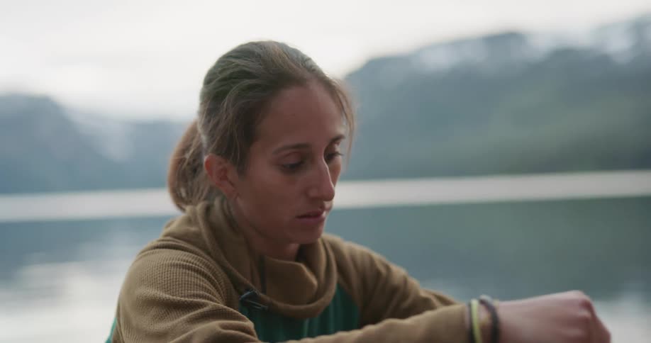 Woman cooking a meal in a small pot over a portable stove while camping