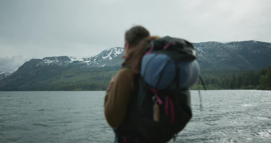 A woman is looking out over the lake on a windy day