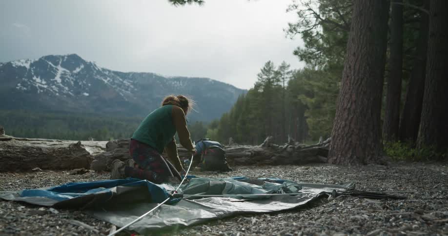 A woman puts poles in a tent as she sets it up