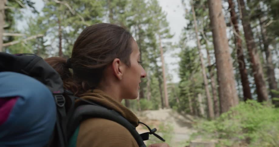 A woman hiking looks around the forest