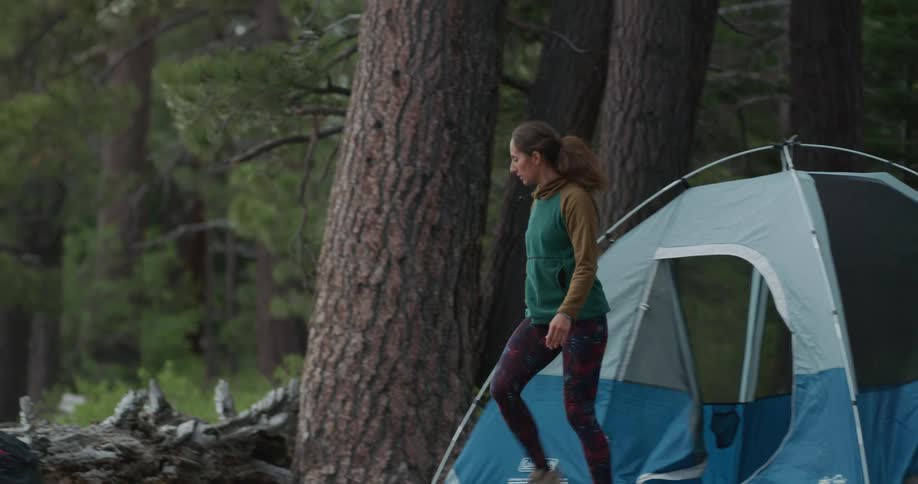 A woman walks outside from a tent and looks around at the wilderness scenery