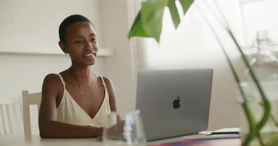 A woman smiling while video chatting on a laptop at a desk