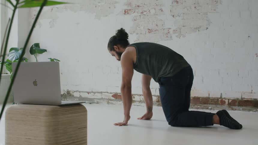 A man arching his back while stretching in a white room
