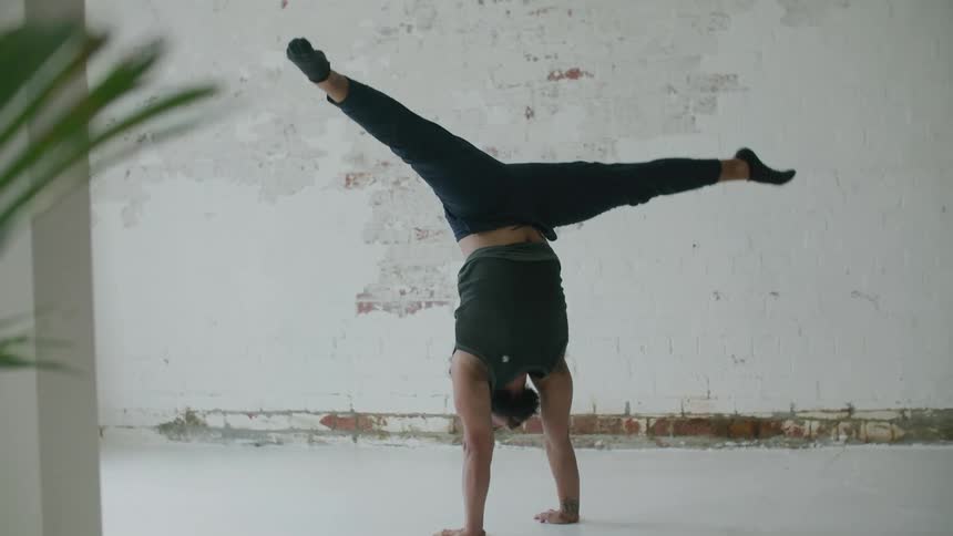 A man doing a handstand performing yoga poses indoors
