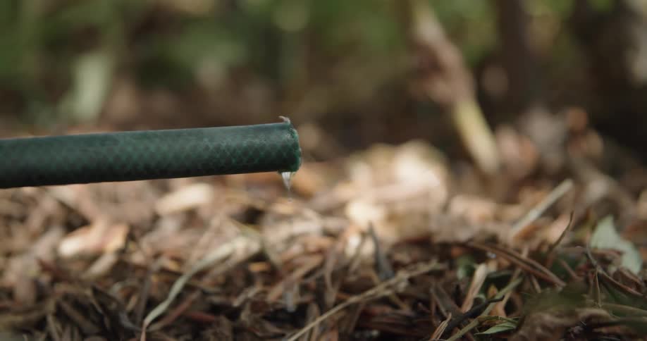 A small hose that is sticking outward slowly drips water from its end