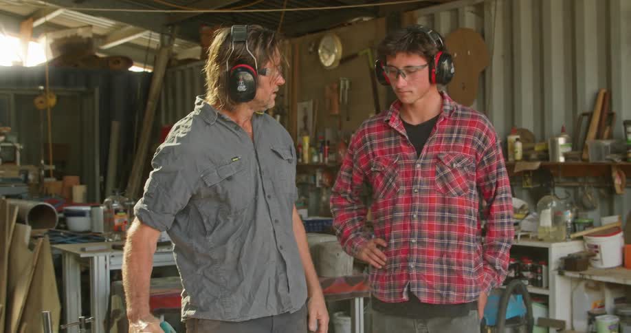 Two coworkers cutting wood in a shop