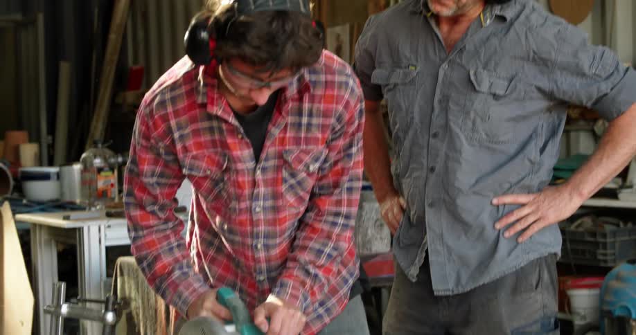Two coworkers that are cutting wood in a shop