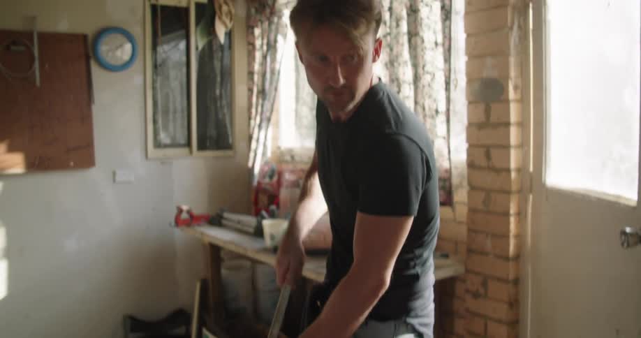 A man sweeping the garage floor with a broom around a vespa scooter