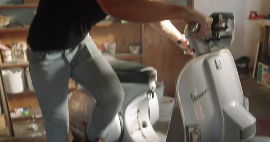 A man that is trying to start a scooter