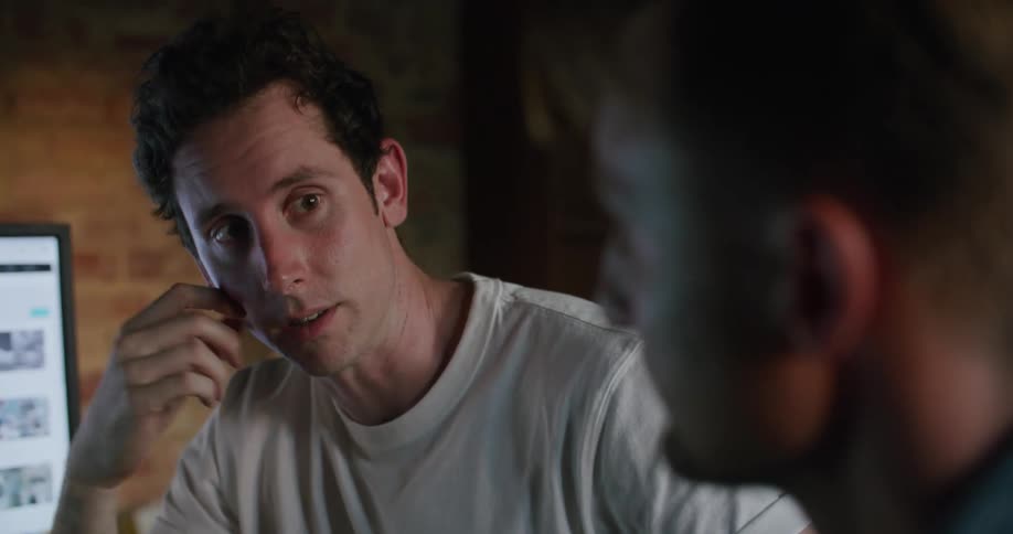 Two men on a meeting inside a dimly lit room talking to each other near a computer screen