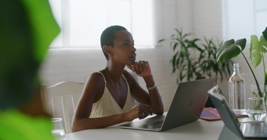 A man and woman talk together sitting at a table with laptops