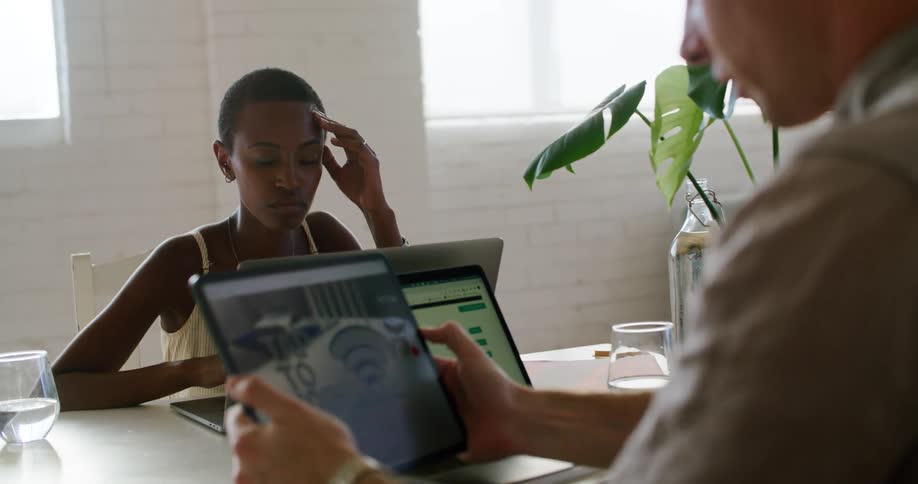Coworkers in a meeting at the office working with tablets and laptops