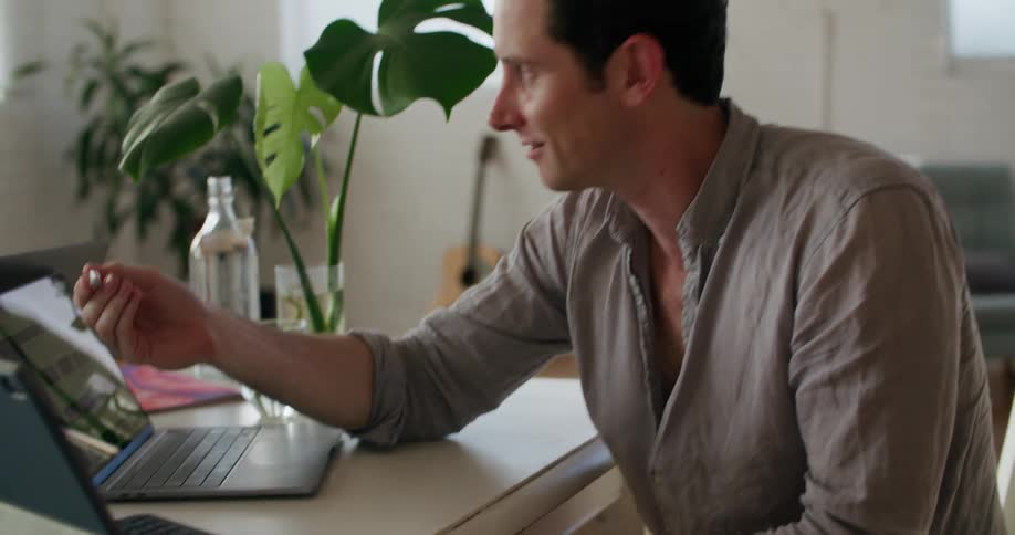 A man and woman working in a casual office high five during a video call on laptops
