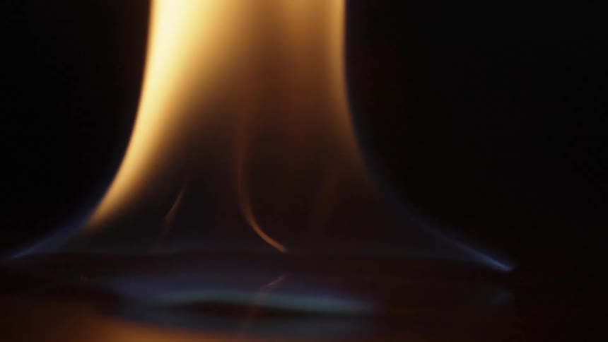 Sparks fly and ignite a flame across a black surface