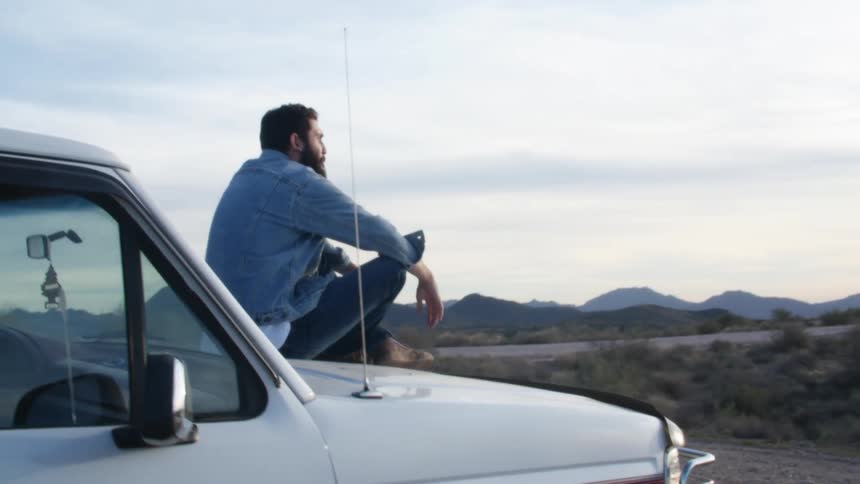 A man sitting on the hood of a truck