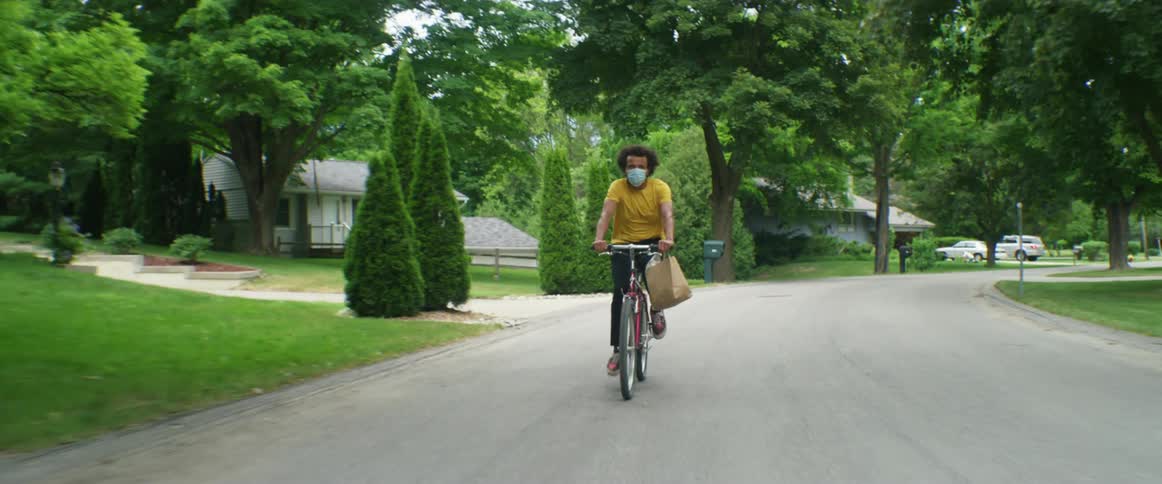 A man that is riding a bicycle on a road with a delivery bag