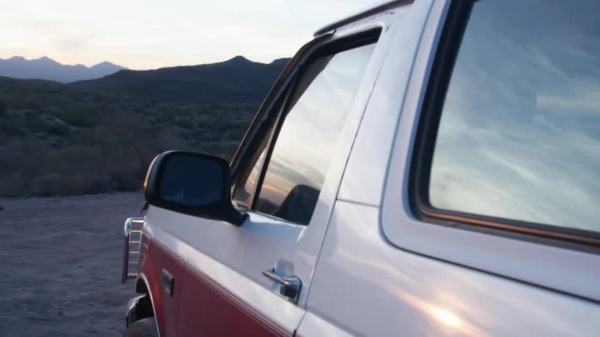 A truck driving over dirt in nature at sunset