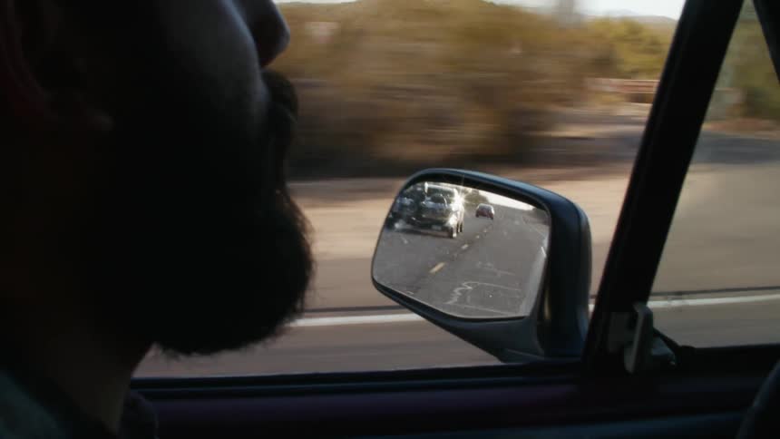 Bearded man driving a pickup truck on a rural road at evening