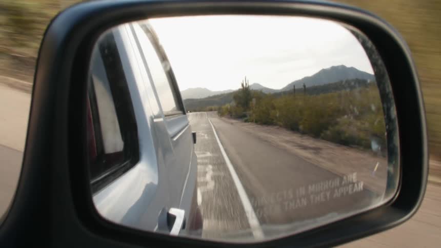 A view out of the side view mirror of a car driving