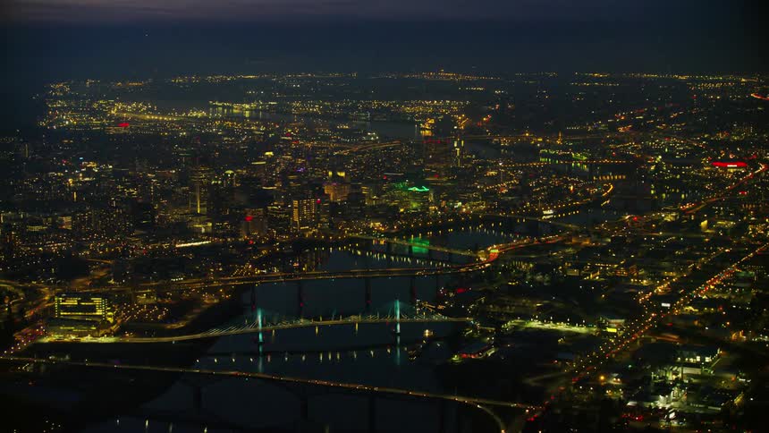 A vast wide nightime aerial of downtown Portland Oregon showing the Willamette River the bridges and the downtown skyscrapers of the beautiful city as seen from the air