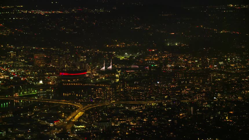 Zoom out reveal night aerial shot of Portland Oregon and beautiful city lights in this high altitude aerial shot