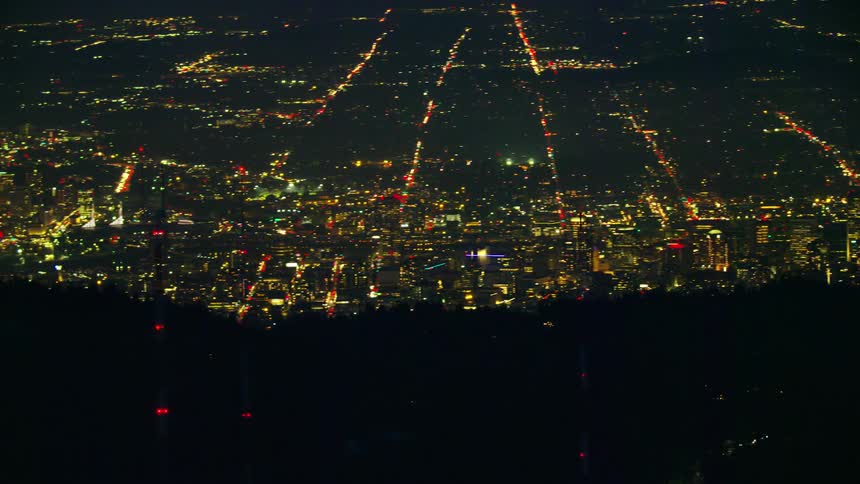 Radio antennae pass in front of the camera as it pans left revealing the entire city of Portland Oregon at night in this vast night aerial shot of the city landscape