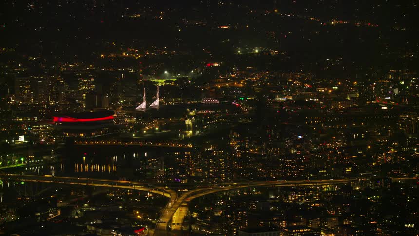 Night aerial of downtown Portland with the lights of the Moda Center lighting up the city lights and I5 highway below