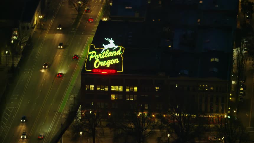 Night aerial shot of the Portland Oregon White Stag Neon Sign as seen from high above the city in this tight aerial