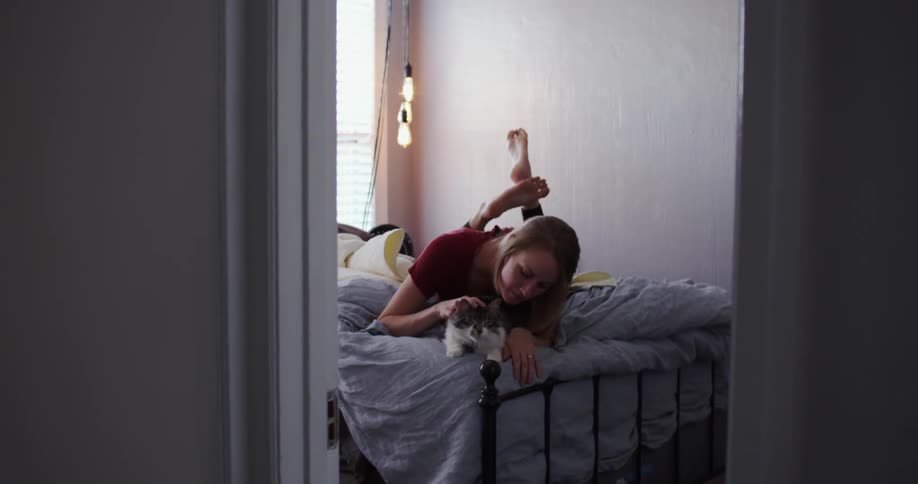 A woman laying on a bed petting a cat