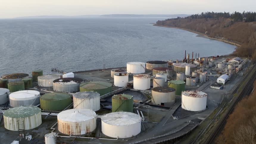 A tank farm and industrial facility is located next to a marine ecosystem