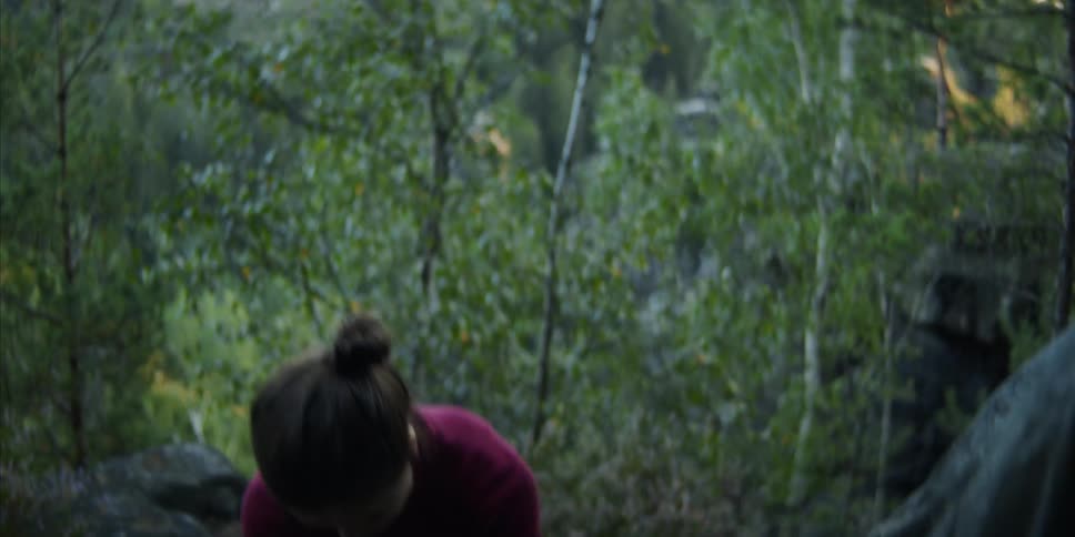 A woman setting a tent up in a forest area