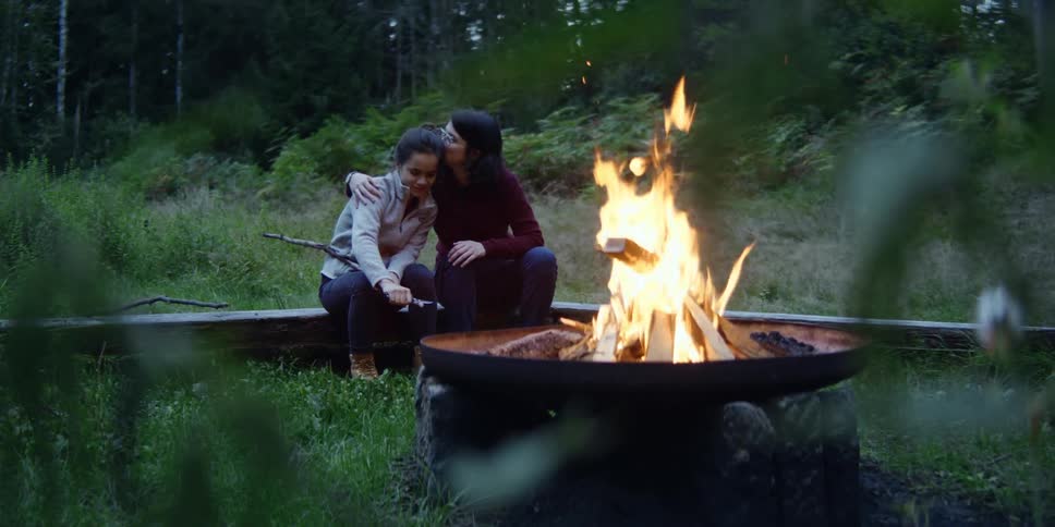 A lesbian couple is sitting at a campfire