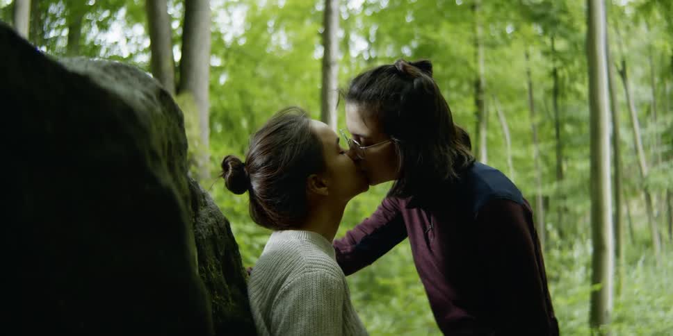 Lesbian couple kisses each other in the woods