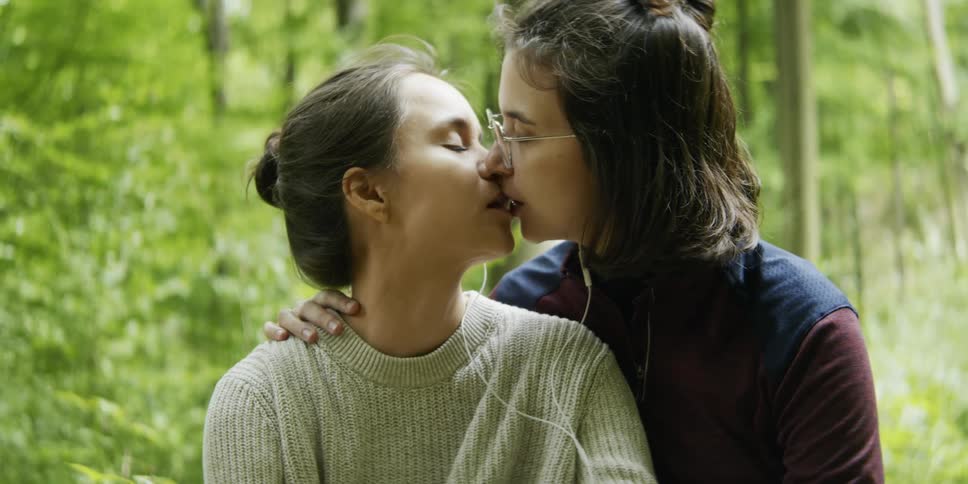 Two women kissing in the forest