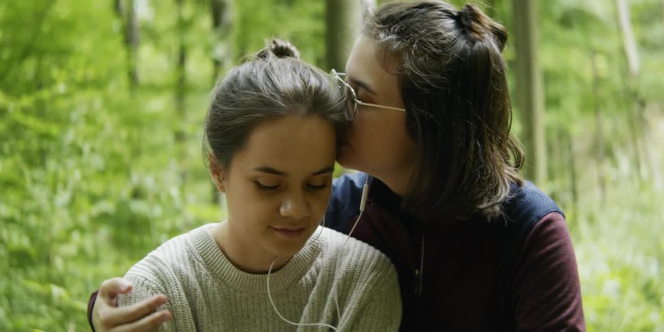 A woman kissing her girlfriend in a forest