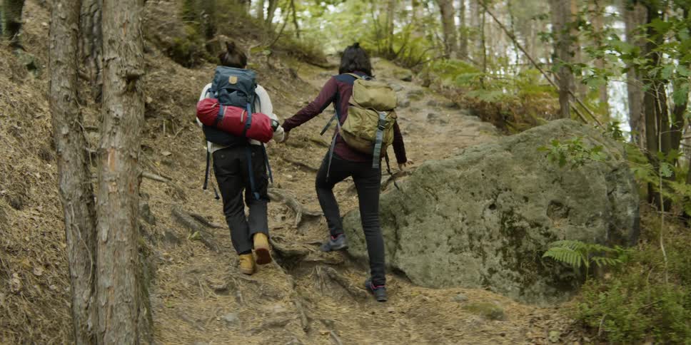 Two women are hiking through a forest