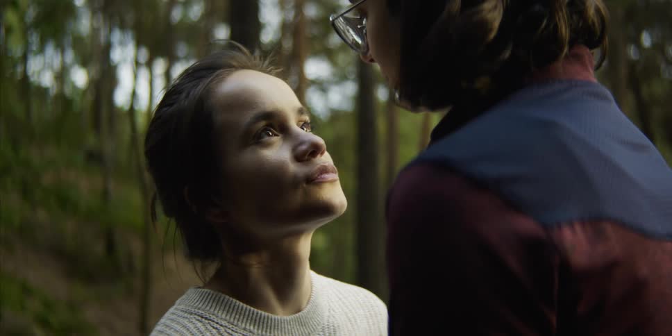 Two women share romantic kiss in forest