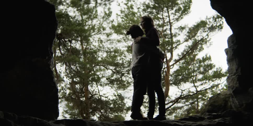 Two women are kissing outdoors in a forest