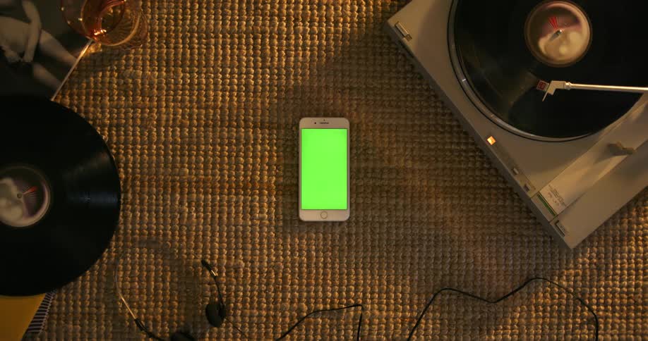A record spins on a record player next to a cell phone