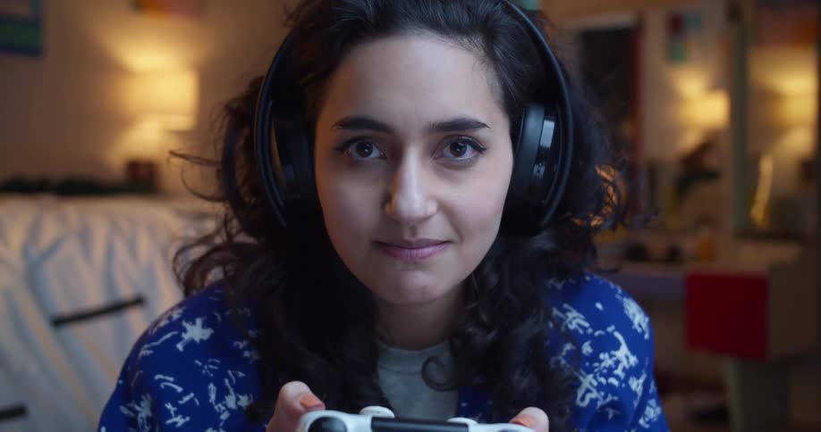 A woman wears a headset and smiles while playing a video game at home