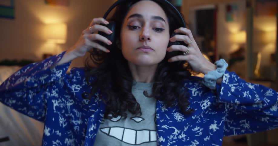 A woman puts on her headphones and plays video games