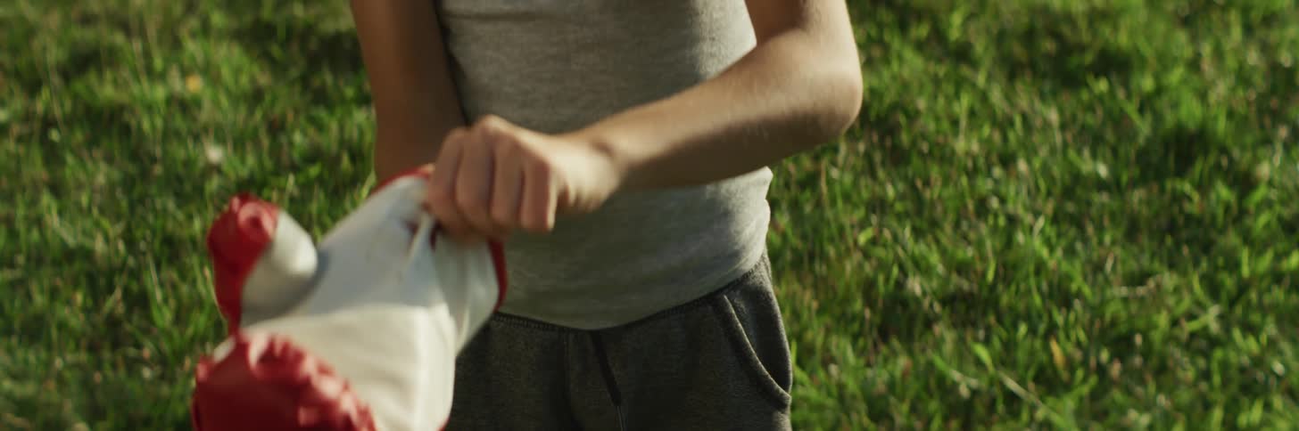 A boy lifts up and puts on boxing gloves